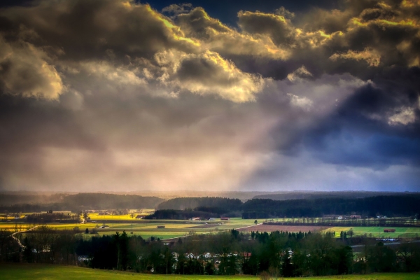 Sommerlandschaft in dramatischer Vorgewitterbeleuchtung mit heftiger Bewölkung und durchdringenden Sonnenstrahlen
